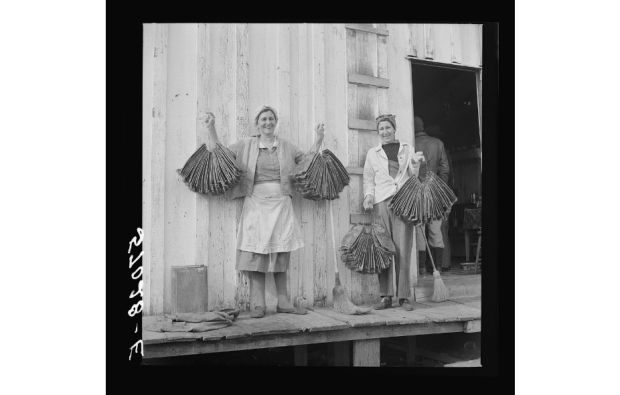 Spanish trapper's wife and sister-in-law holding dried muskrat skins in front of their camp